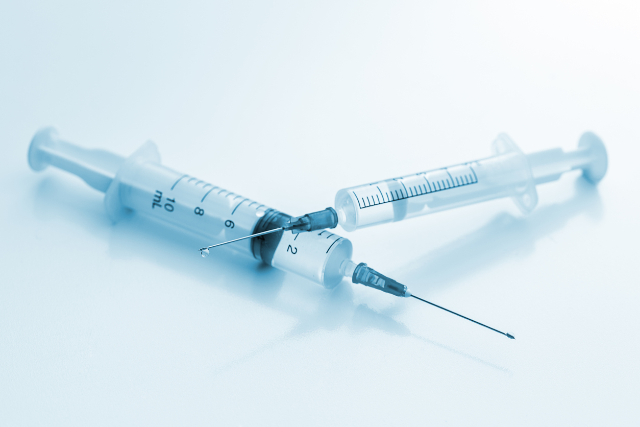 disposable syringes with medical anesthetic solution and a drop on a needle. Taken in studio with a 5D mark III.